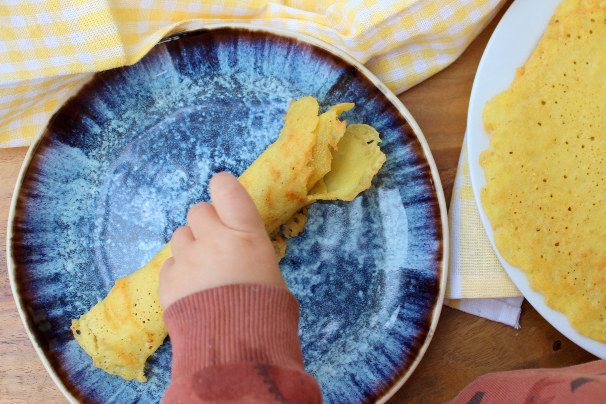 kinderhand greift nach hirsepfannkuchen