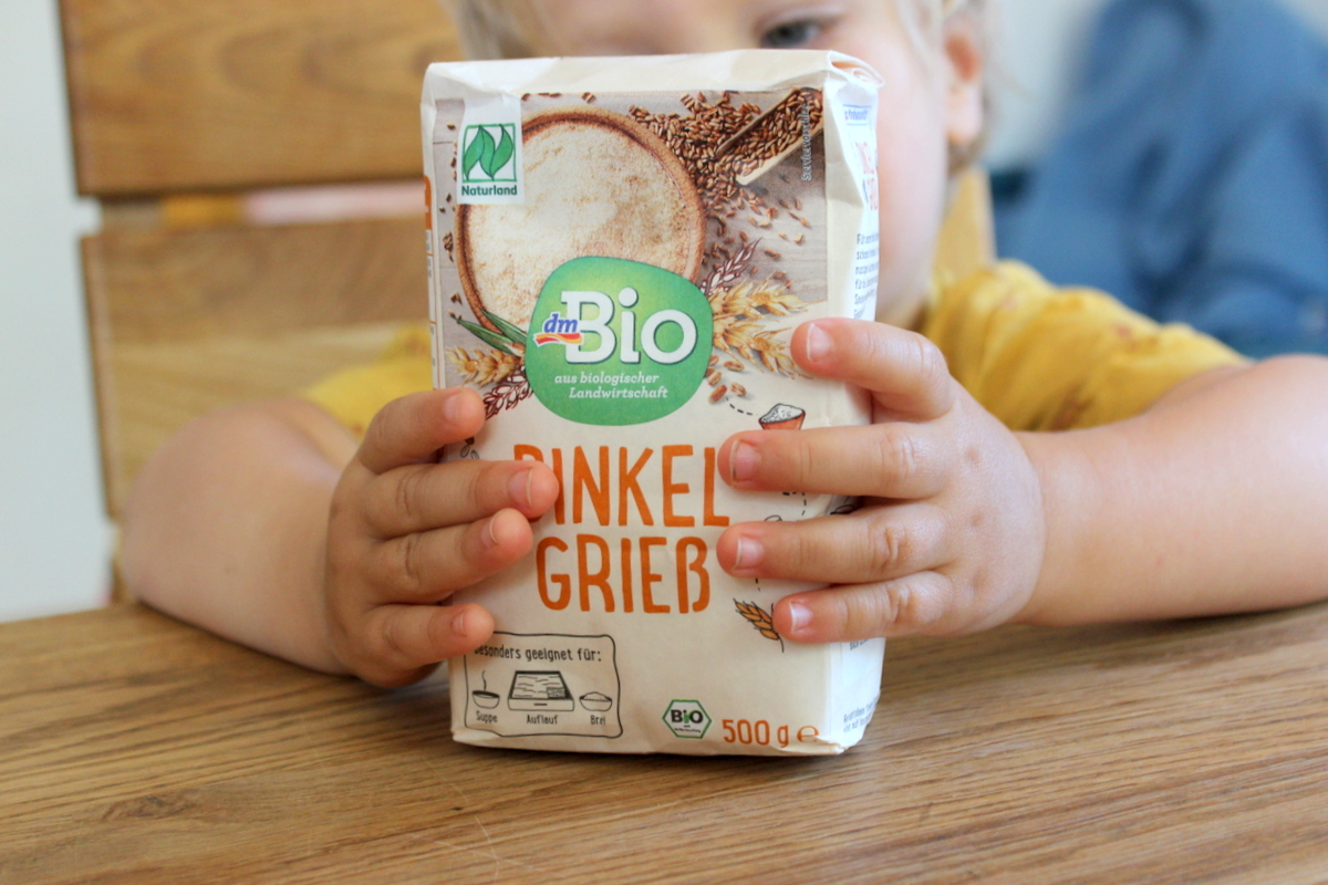 baby hält dinkelgrieß in der Hand