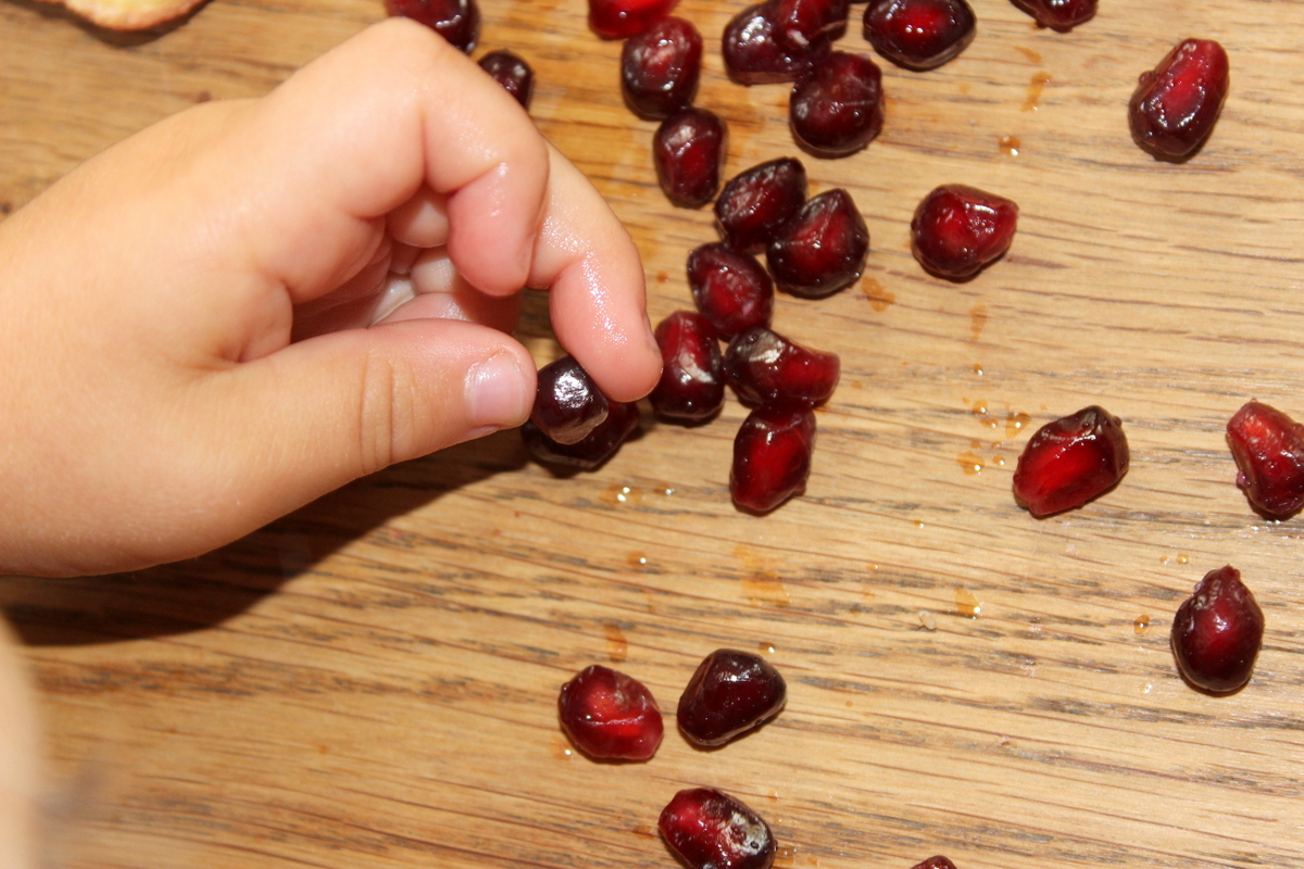 baby isst granatapfelkerne mit den Fingerspitzen