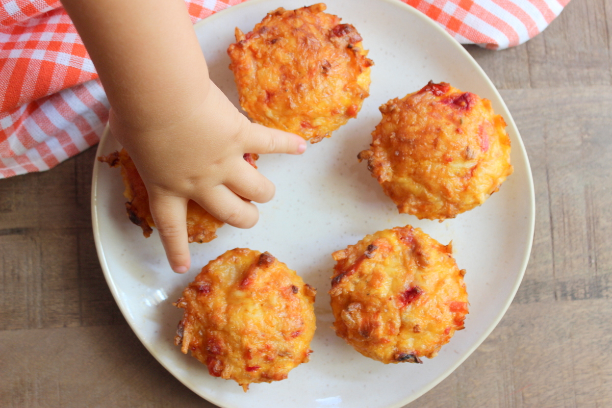 kinderhand nimmt einen gemüsemuffin vom teller