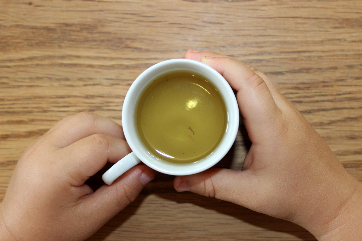 baby trinkt kamillentee aus einer kleinen tasse