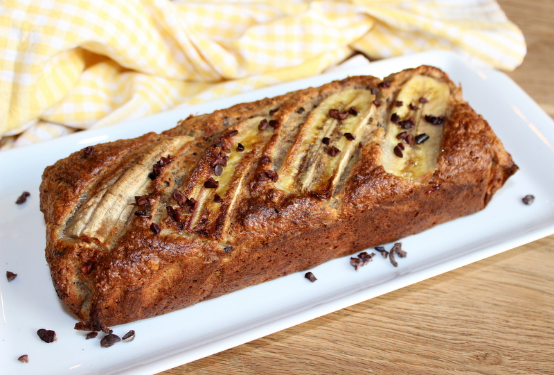 hafer bananenbrot auf einem weißen, langen Teller mit Banane und Kakaonibs verziert