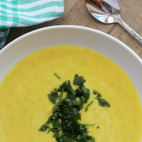 gelbe zucchini-linsen-suppe mit koriander in der mitte